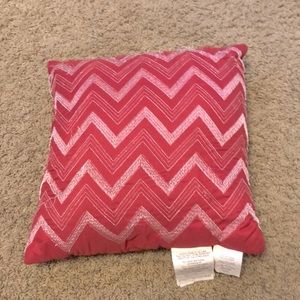 This is a pink pillow with zig zags in the front.